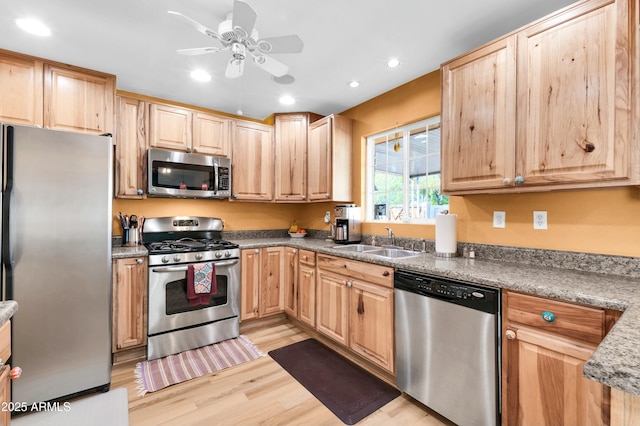 kitchen with appliances with stainless steel finishes, light brown cabinetry, light hardwood / wood-style floors, and sink