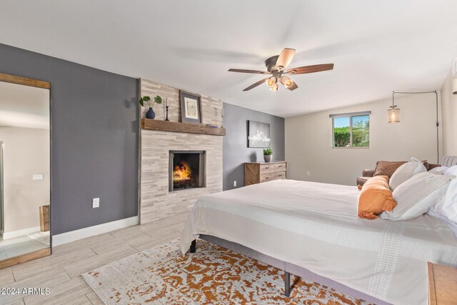 bedroom featuring ceiling fan, wood-type flooring, and a fireplace