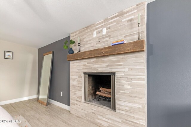 bedroom with a large fireplace, ceiling fan, and light hardwood / wood-style flooring