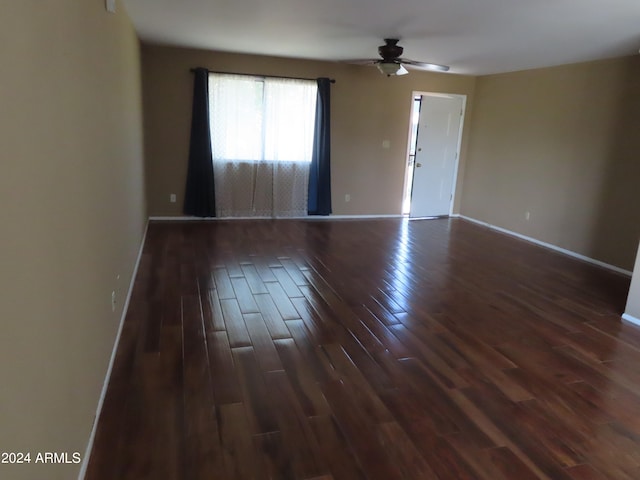 unfurnished room featuring dark wood-type flooring and ceiling fan