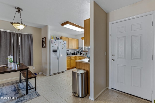 kitchen with pendant lighting, white refrigerator with ice dispenser, light brown cabinets, and light tile patterned flooring