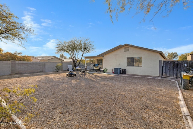 back of property with cooling unit, an outdoor fire pit, and a patio area