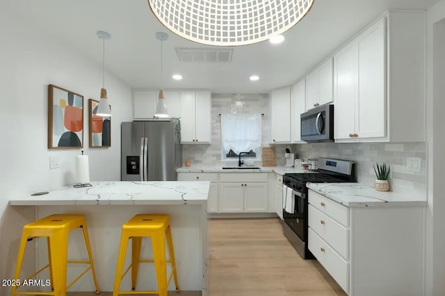 kitchen with stainless steel appliances, white cabinetry, sink, and a kitchen breakfast bar