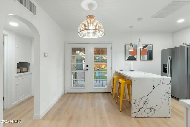 kitchen with decorative light fixtures, french doors, white cabinets, and stainless steel refrigerator with ice dispenser