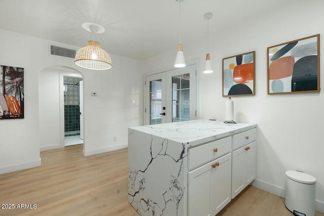 kitchen featuring decorative light fixtures, light stone countertops, kitchen peninsula, and white cabinets