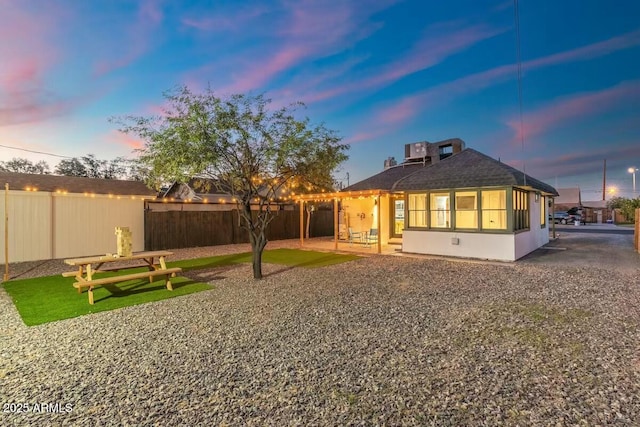 back house at dusk featuring a patio and a sunroom