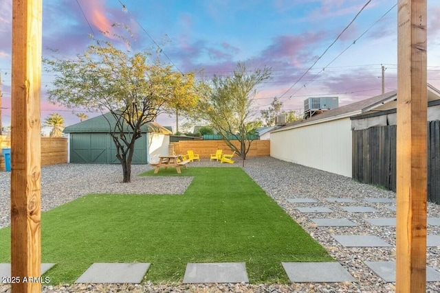 yard at dusk with cooling unit and a storage unit