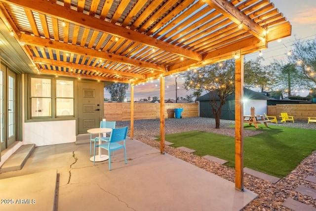 patio terrace at dusk with a pergola, a lawn, and a storage unit