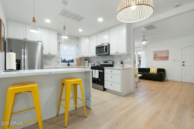 kitchen with white cabinetry, appliances with stainless steel finishes, and a kitchen bar