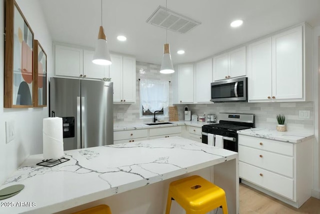 kitchen featuring pendant lighting, sink, a breakfast bar area, stainless steel appliances, and white cabinets