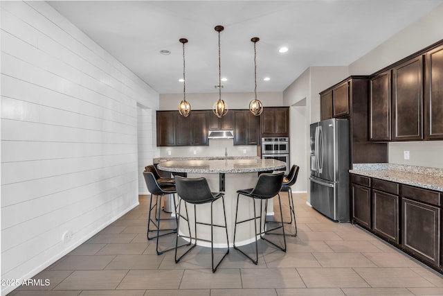 21004 E Sunset Dr, Queen Creek, AZ 85142 - kitchen with a kitchen breakfast bar, under cabinet range hood, dark brown cabinets, light stone countertops, and stainless steel appliances