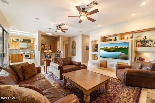 living room with built in features, ceiling fan, and light tile patterned flooring