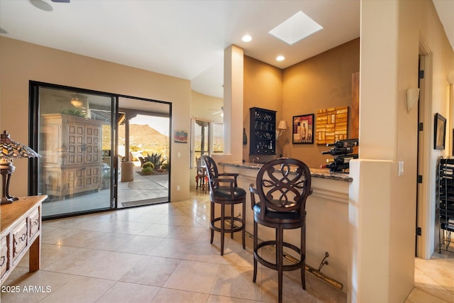 bar featuring light stone countertops, light tile patterned floors, and ceiling fan