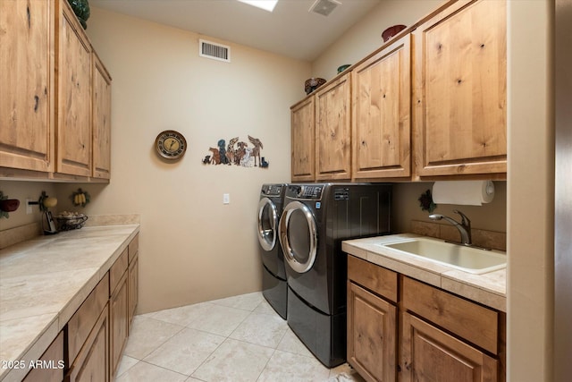 washroom with cabinets, light tile patterned floors, sink, and washing machine and dryer