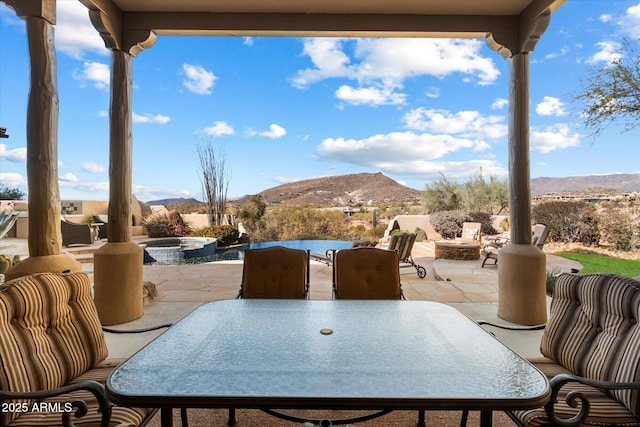 view of patio / terrace featuring a mountain view and an in ground hot tub