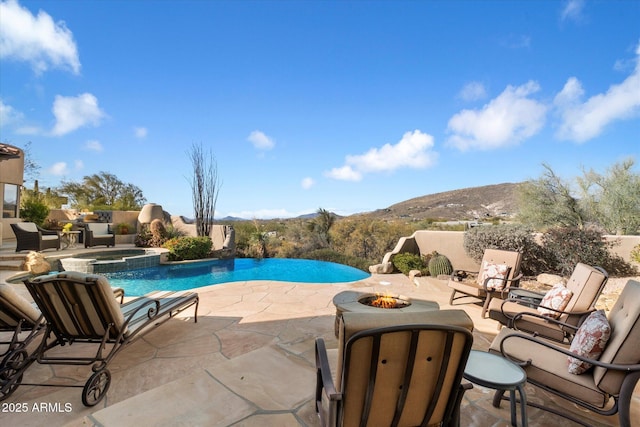 view of swimming pool featuring an in ground hot tub, a mountain view, a fire pit, and a patio