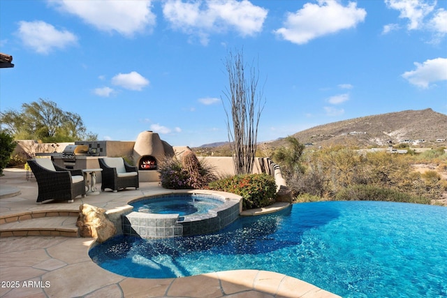 view of pool featuring an in ground hot tub, a mountain view, and a patio