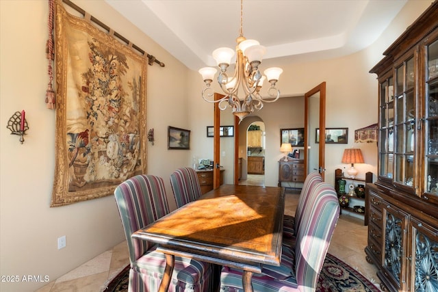 tiled dining space with a tray ceiling and an inviting chandelier