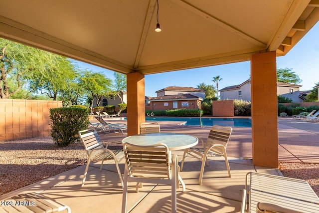 view of patio / terrace with a community pool, fence, outdoor dining area, and a gazebo