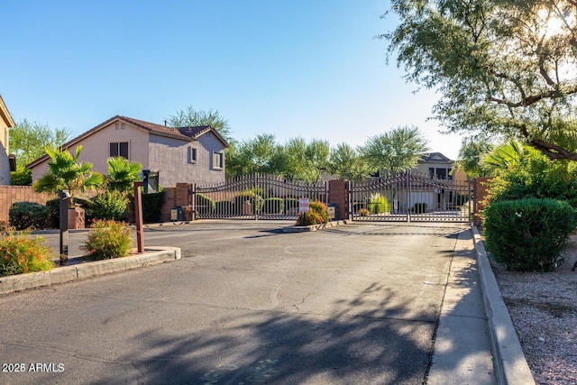 view of road featuring curbs, a gated entry, and a gate