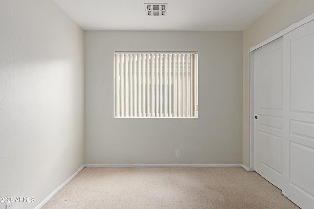 unfurnished bedroom featuring light carpet, baseboards, visible vents, and a closet