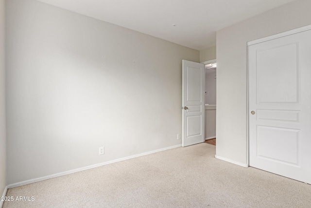 unfurnished bedroom featuring light carpet and baseboards