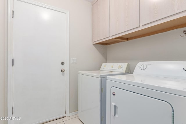 clothes washing area with cabinet space, light tile patterned floors, and washer and clothes dryer