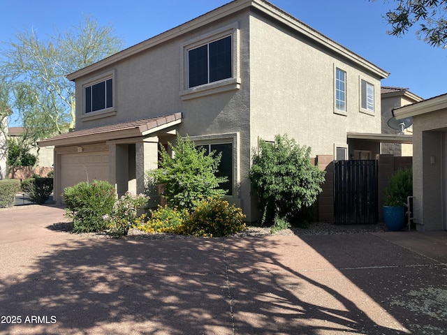 view of front of house featuring concrete driveway, an attached garage, a gate, and stucco siding