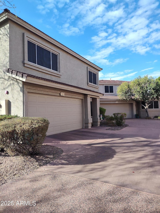 view of front of property with driveway, an attached garage, and stucco siding