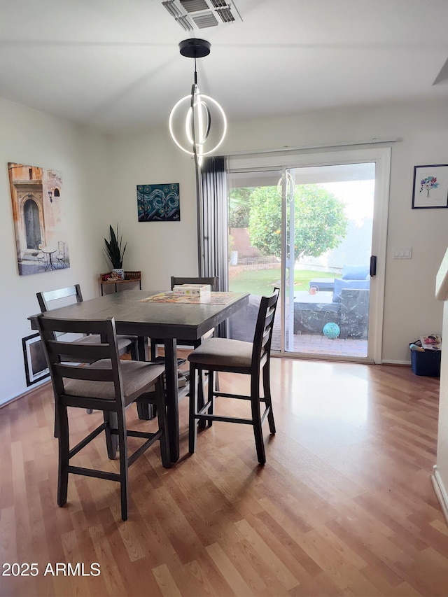 dining room with visible vents, light wood finished floors, and an inviting chandelier