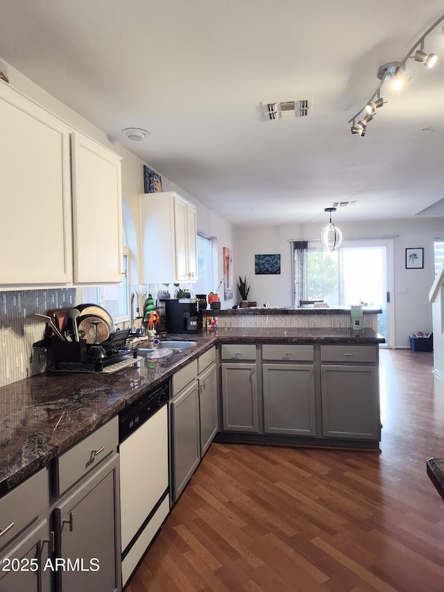 kitchen with white dishwasher, a peninsula, dark wood-type flooring, a sink, and gray cabinets