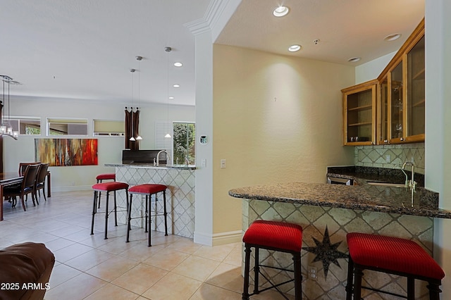bar featuring baseboards, decorative backsplash, a sink, and light tile patterned floors