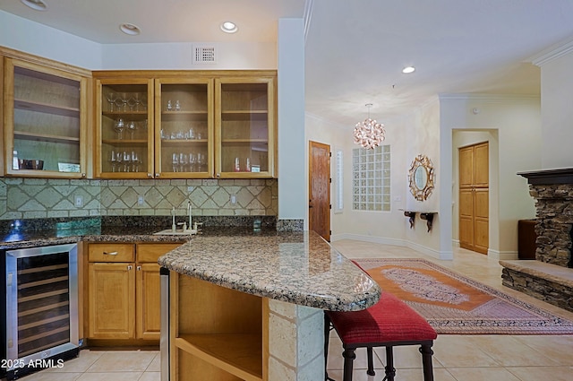 bar with visible vents, crown molding, light tile patterned floors, a sink, and beverage cooler