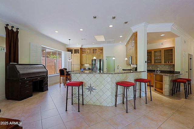 kitchen featuring appliances with stainless steel finishes, decorative backsplash, a breakfast bar area, and a peninsula