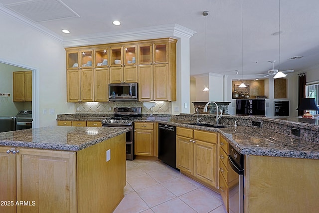 kitchen featuring visible vents, ornamental molding, washer and dryer, a sink, and appliances with stainless steel finishes