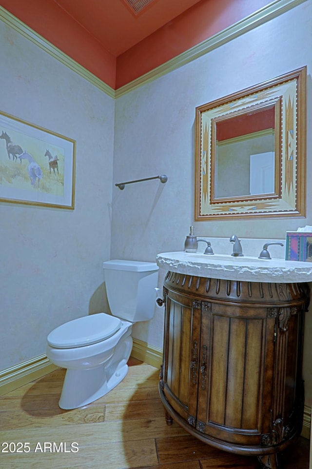 half bath featuring toilet, baseboards, wood finished floors, and vanity