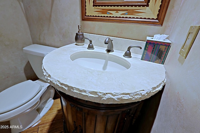 bathroom featuring toilet, wood finished floors, and vanity