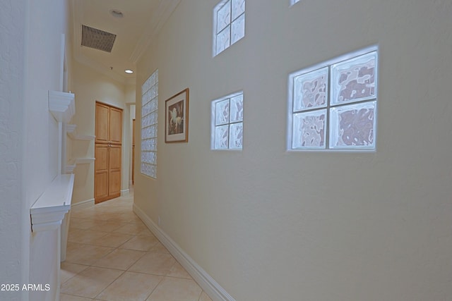hall featuring crown molding, baseboards, visible vents, and light tile patterned floors