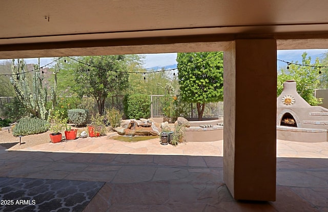 view of patio with a lit fireplace and a fenced backyard
