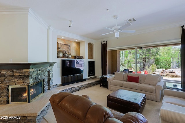 living area with a stone fireplace, a ceiling fan, crown molding, and visible vents