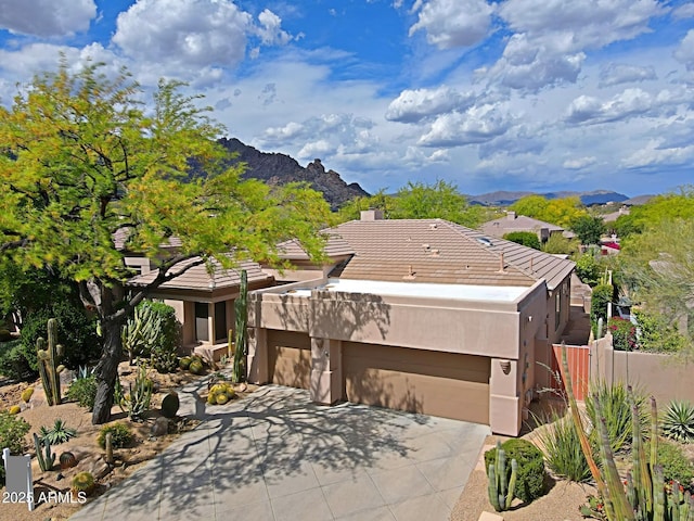 view of front of home featuring a garage, fence, a mountain view, and stucco siding