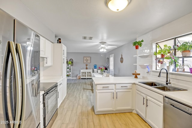 kitchen featuring visible vents, white cabinets, a sink, appliances with stainless steel finishes, and a peninsula