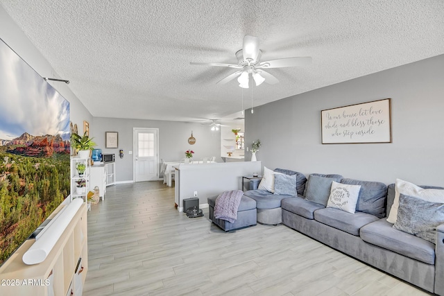 living area with baseboards, a ceiling fan, wood finished floors, and a textured ceiling