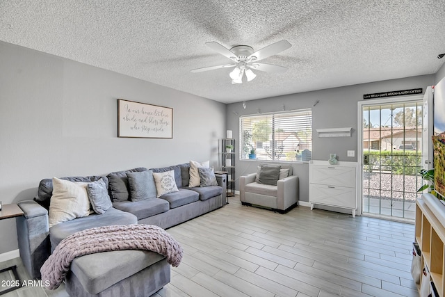 living room with light wood-type flooring, a ceiling fan, baseboards, and a textured ceiling
