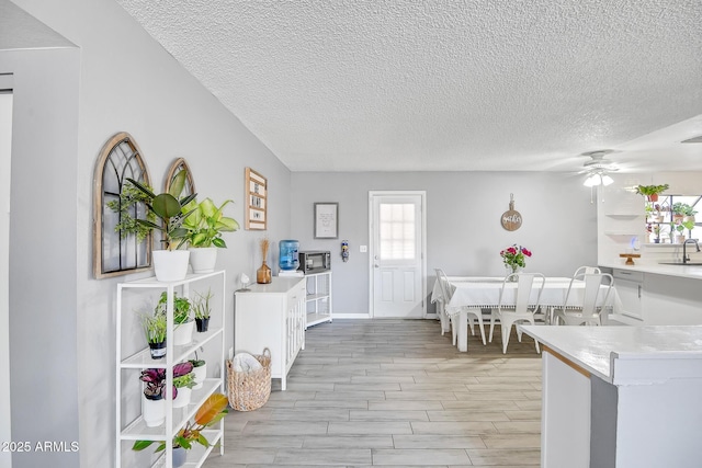 dining room with baseboards, light wood-style flooring, a textured ceiling, and a ceiling fan