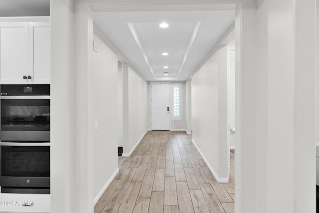 hall featuring a raised ceiling and light wood-type flooring