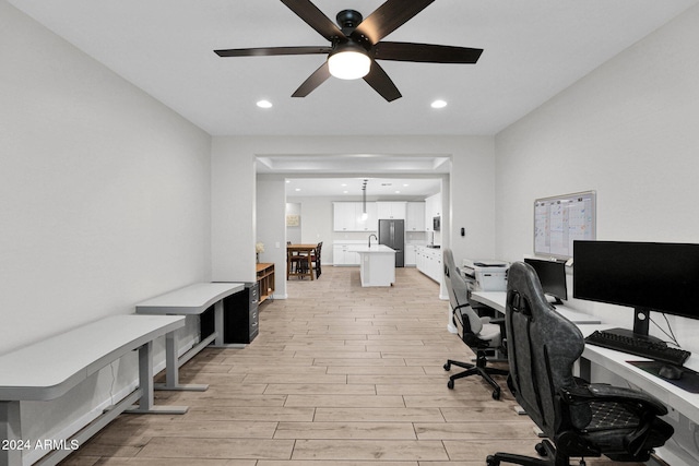 office space featuring ceiling fan, sink, and light hardwood / wood-style floors