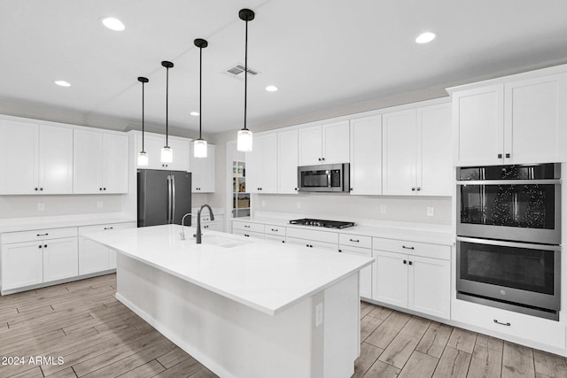 kitchen with pendant lighting, white cabinets, sink, and appliances with stainless steel finishes