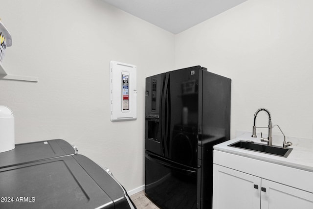 laundry room with cabinets, electric panel, light hardwood / wood-style floors, and sink