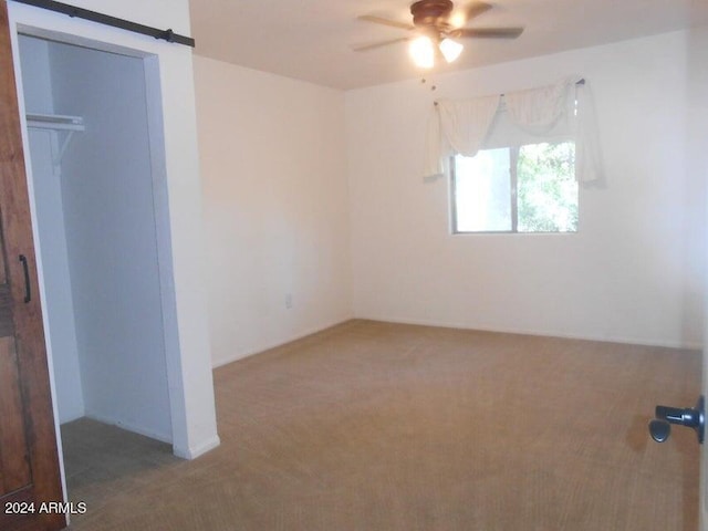 unfurnished bedroom with a closet, carpet floors, and a barn door